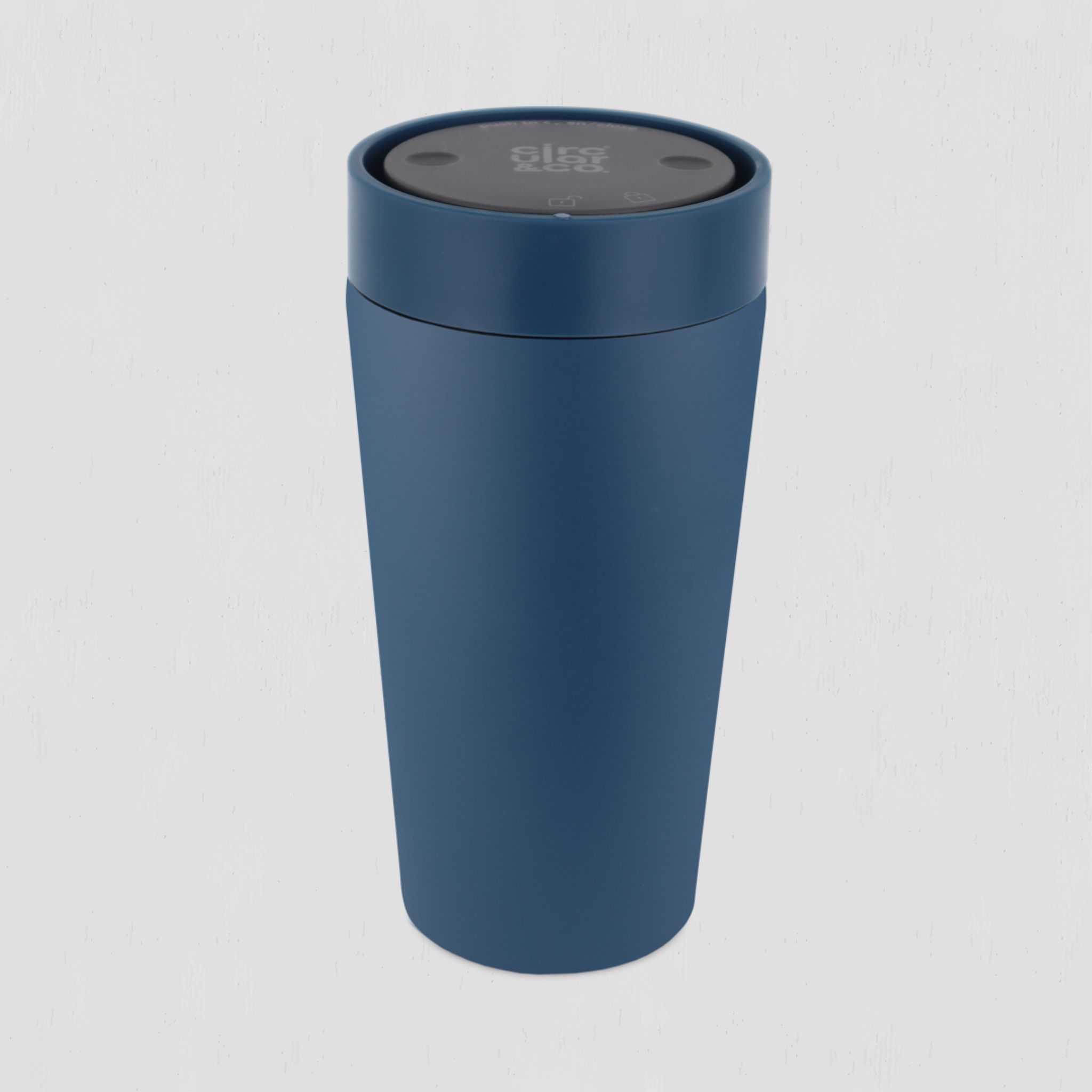A matte navy blue insulated travel tumbler with a matching navy lid and a black circular top insert, shown on a light gray background.
