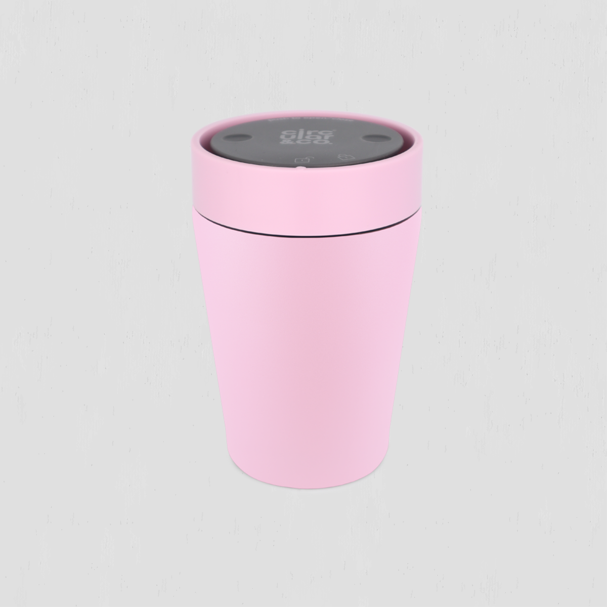 A light pink cylindrical travel tumbler with a dark gray lid featuring a circular control panel, shown on a light gray background.