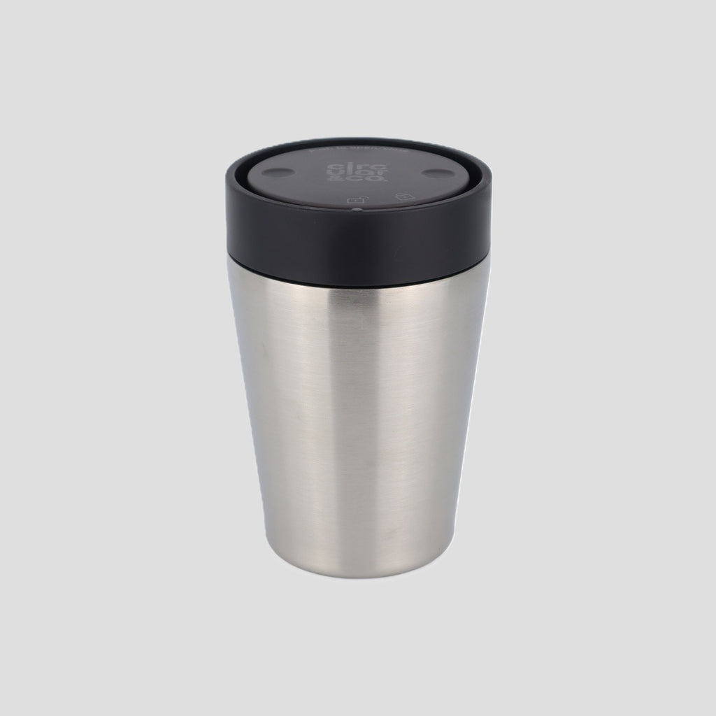 A stainless steel travel tumbler with a black lid, shown on a solid light gray background.