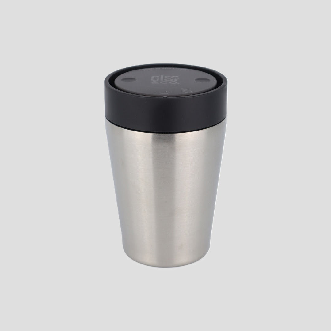 A stainless steel travel tumbler with a black lid, shown on a solid light gray background.