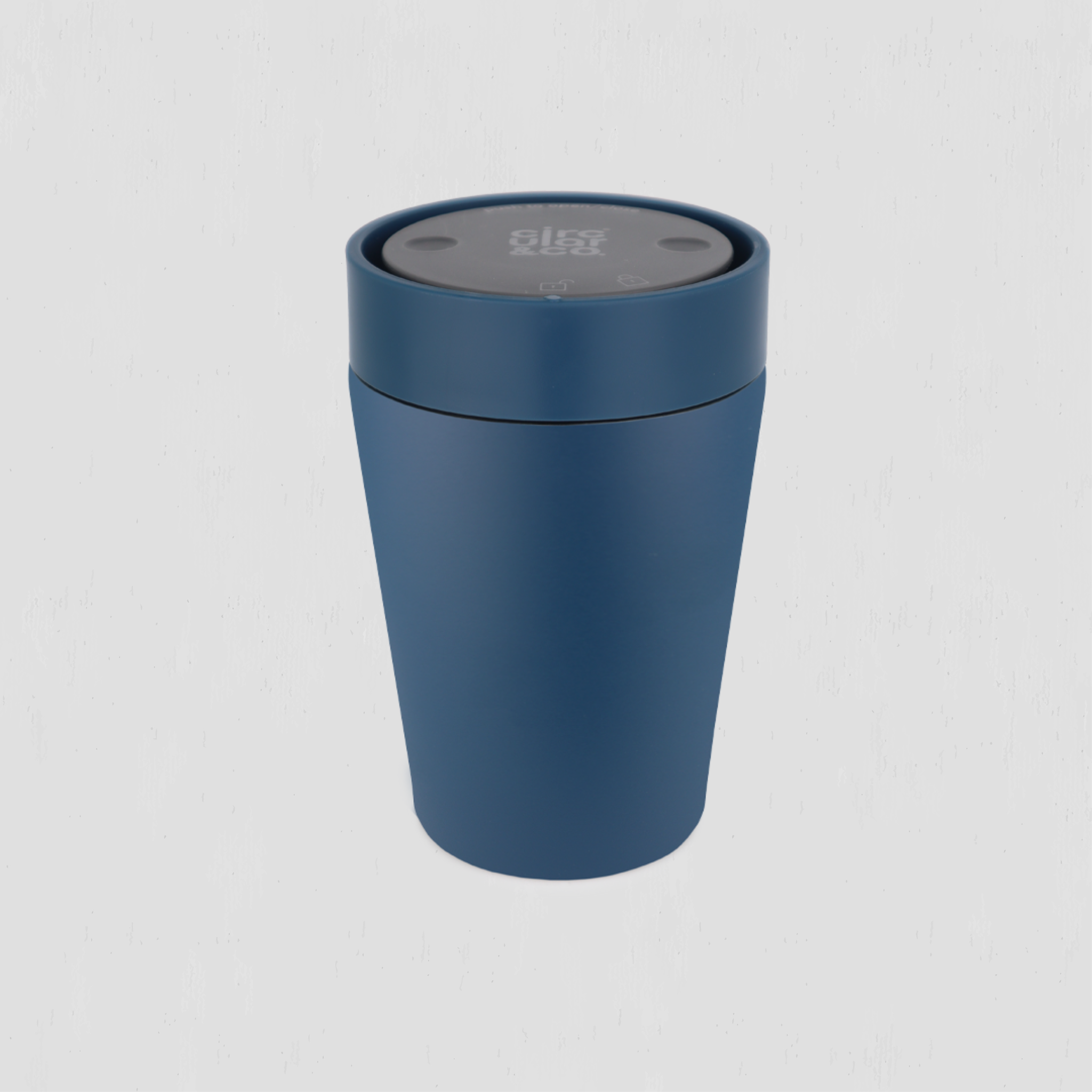A matte blue cylindrical cup with a dark gray circular lid, shown on a light gray background.