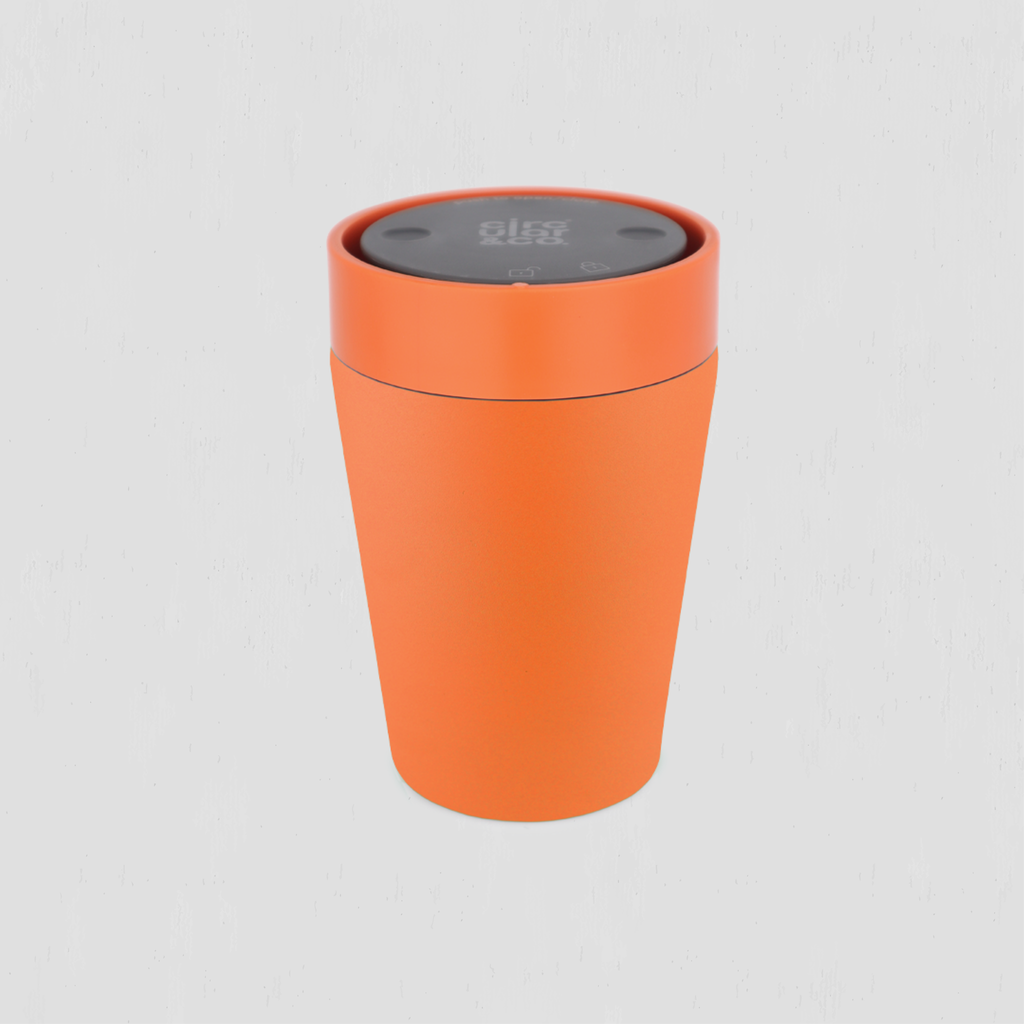 An orange cylindrical cup or container with a dark gray lid, shown on a light gray background. 