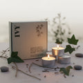 Set of three candles in front of a branded box in twilight