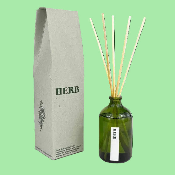 Green bottle with reeds and packaging labeled 'HERB' on a green background