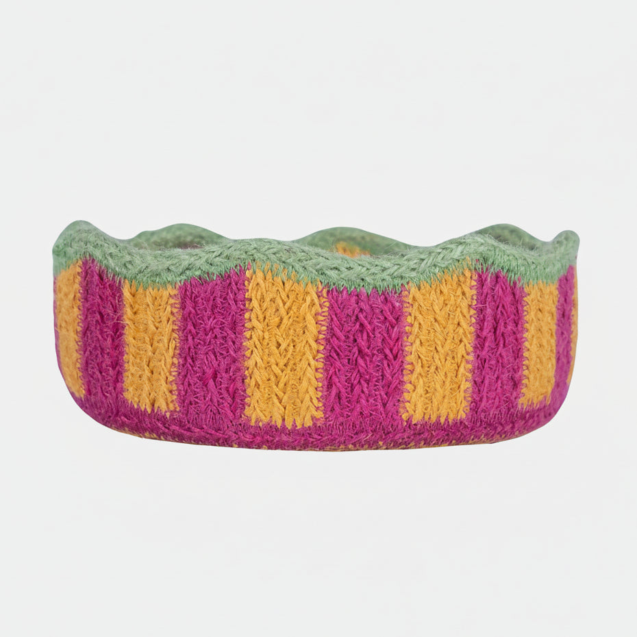 jute basket with green, pink, and yellow stripes on a grey background