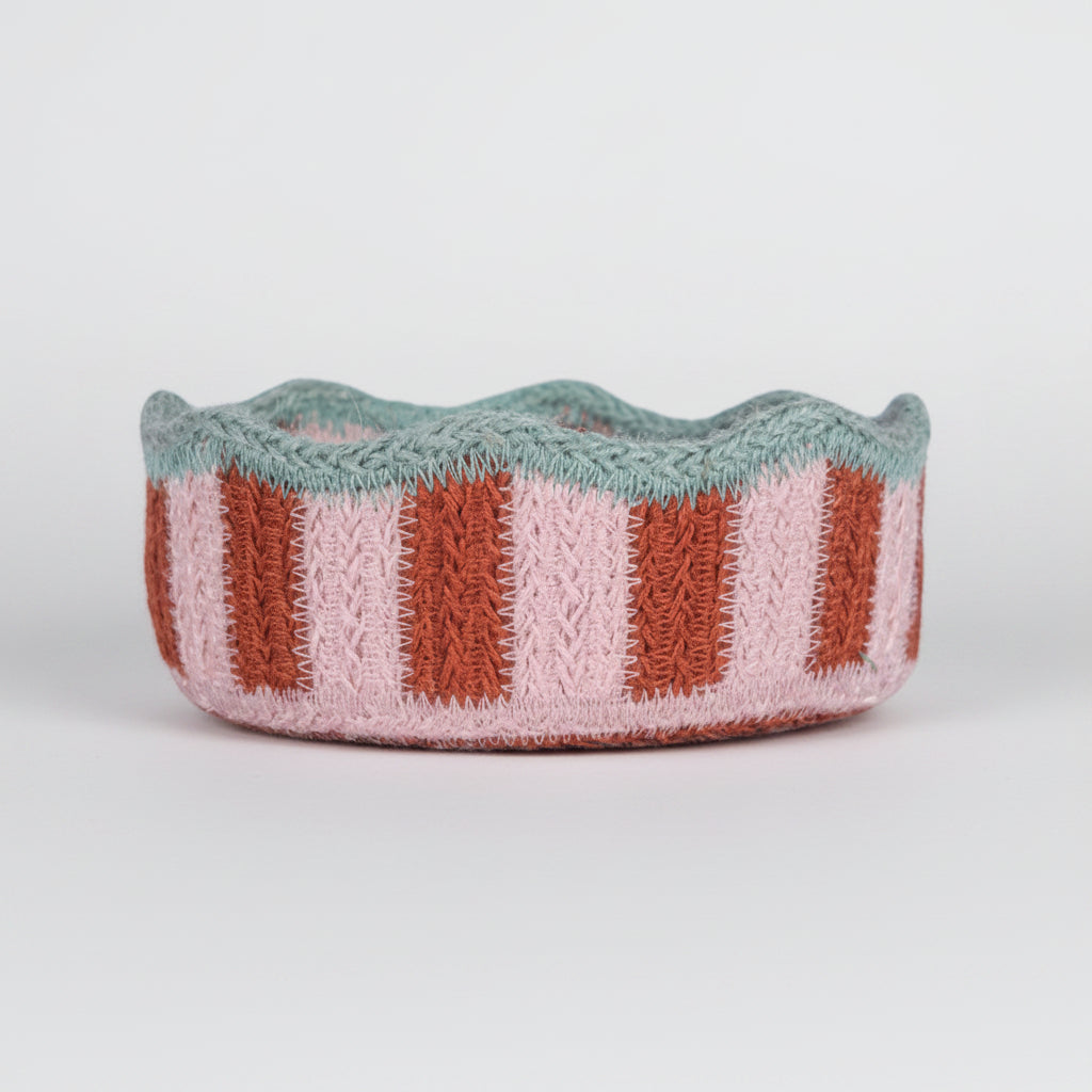 Jute basket with wavy edge and striped pattern on a white background
