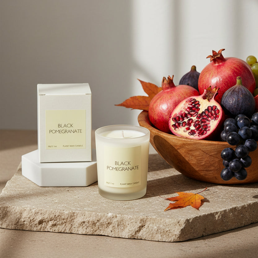 A black pomegranate scented candle in a clear glass jar 