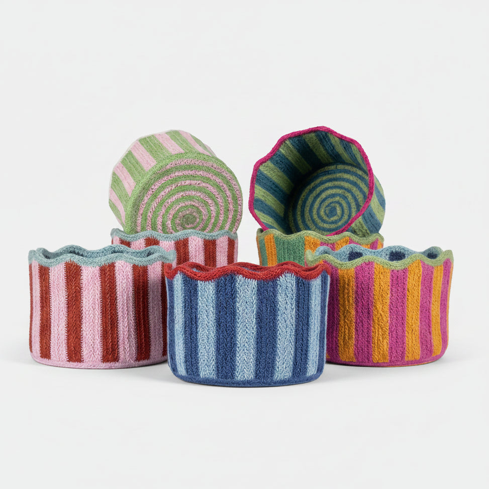 Set of colorful striped jute containers on a grey background