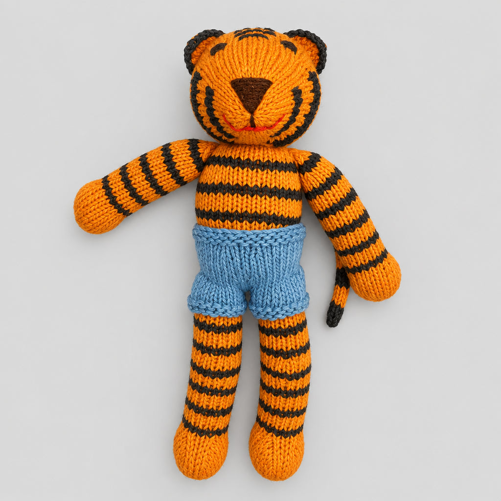 A hand-knitted tiger doll with orange and black stripes, wearing light blue shorts. 