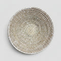 A round woven basket or tray made from natural fibers, photographed from above on a white background with a black handwritten signature reading 'La Bowl' below it.