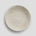 A round woven straw bowl in a light beige and white color.