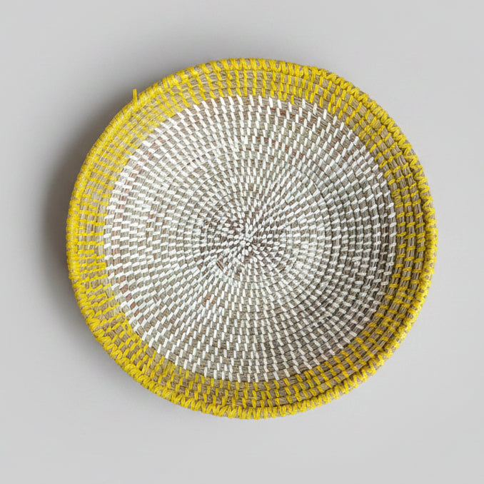 A round woven basket with a bright yellow rim and a light gray body.