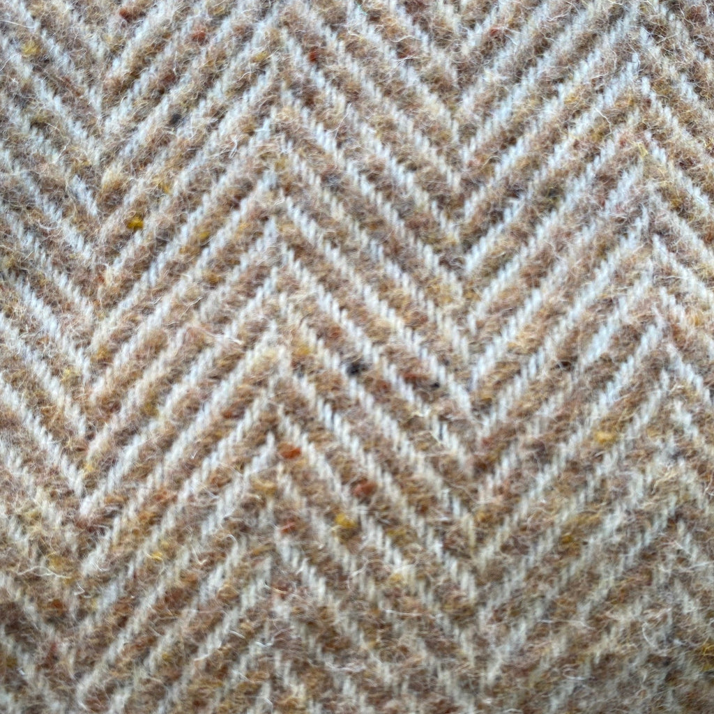 Close-up of a textured blanket with a herringbone pattern in light brown and brown tones.