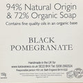 A brown cardboard box with a white label reading '94% Natural Origin & 72% Organic Soap' and 'BLACK POMEGRANATE,' photographed on a wooden surface.