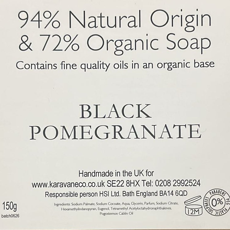 A brown cardboard box with a white label reading '94% Natural Origin & 72% Organic Soap' and 'BLACK POMEGRANATE,' photographed on a wooden surface.