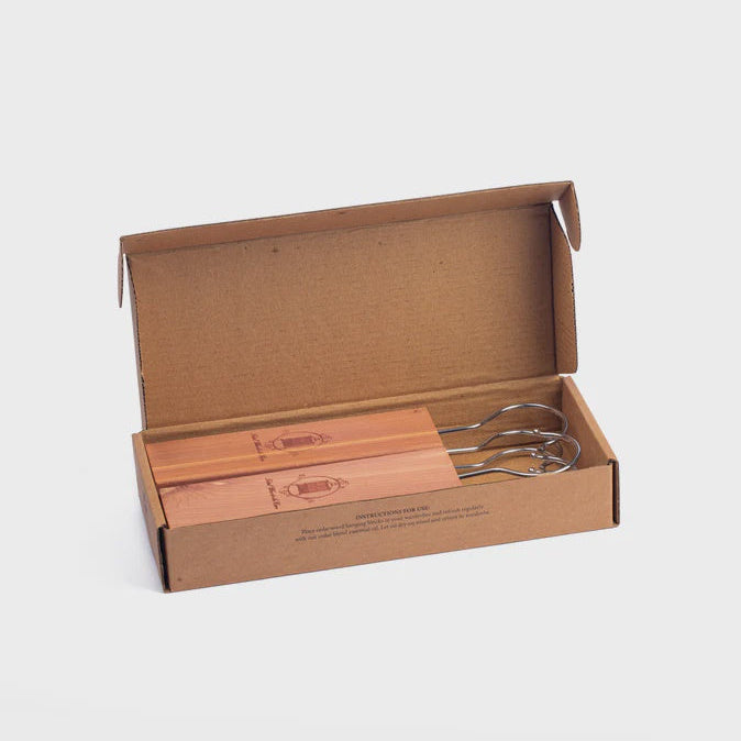 Set of cedar wood hanging blocks in a cardboard box on a light gray background