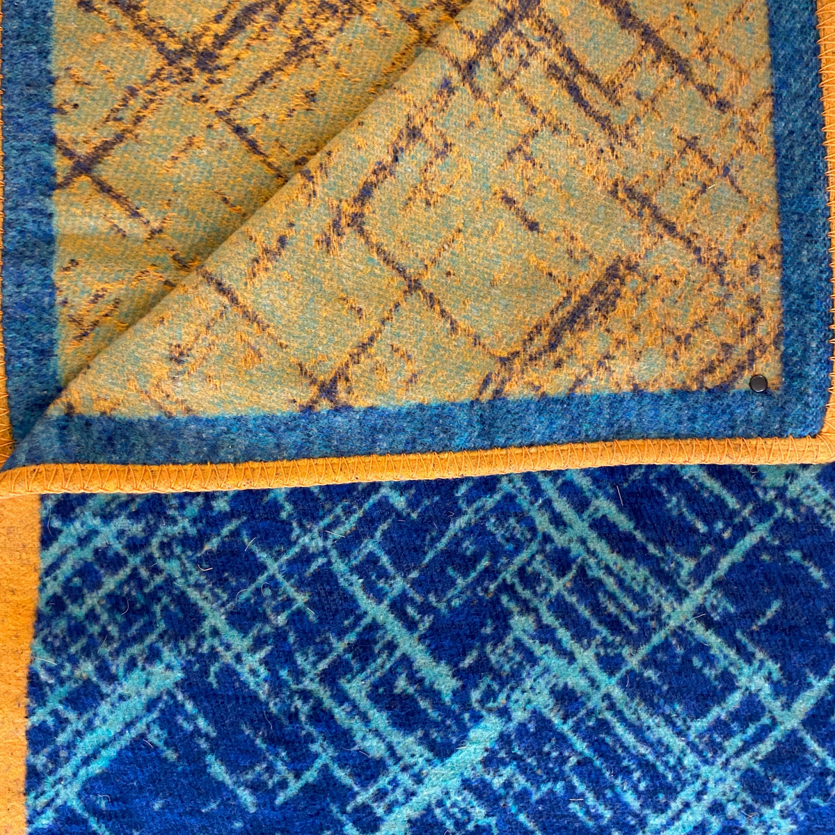 blanket detail reversable one side dark blue with light blue random lines the other side mustard with pale blue