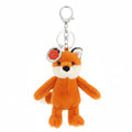 A small plush fox keychain in orange, cream, and black, attached to a silver metal key ring and clasp, with a round red and white tag on a plain white background.