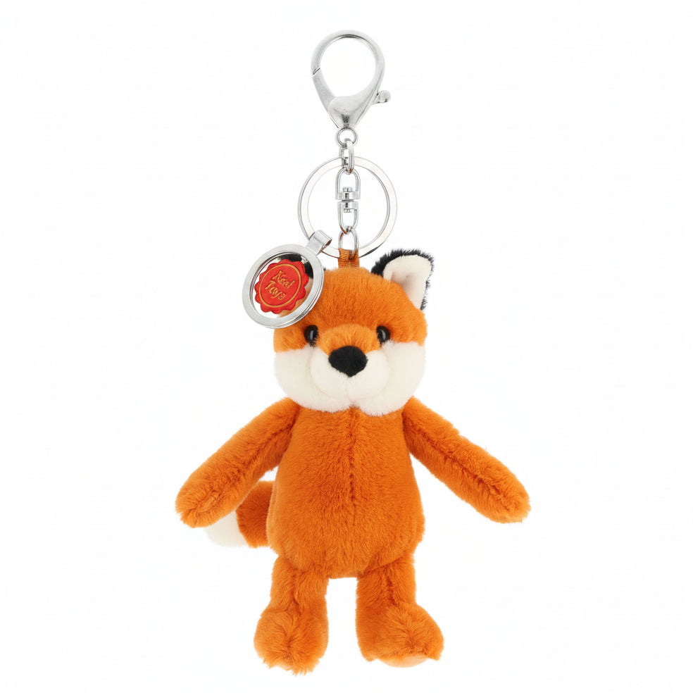 A small plush fox keychain in orange, cream, and black, attached to a silver metal key ring and clasp, with a round red and white tag on a plain white background.