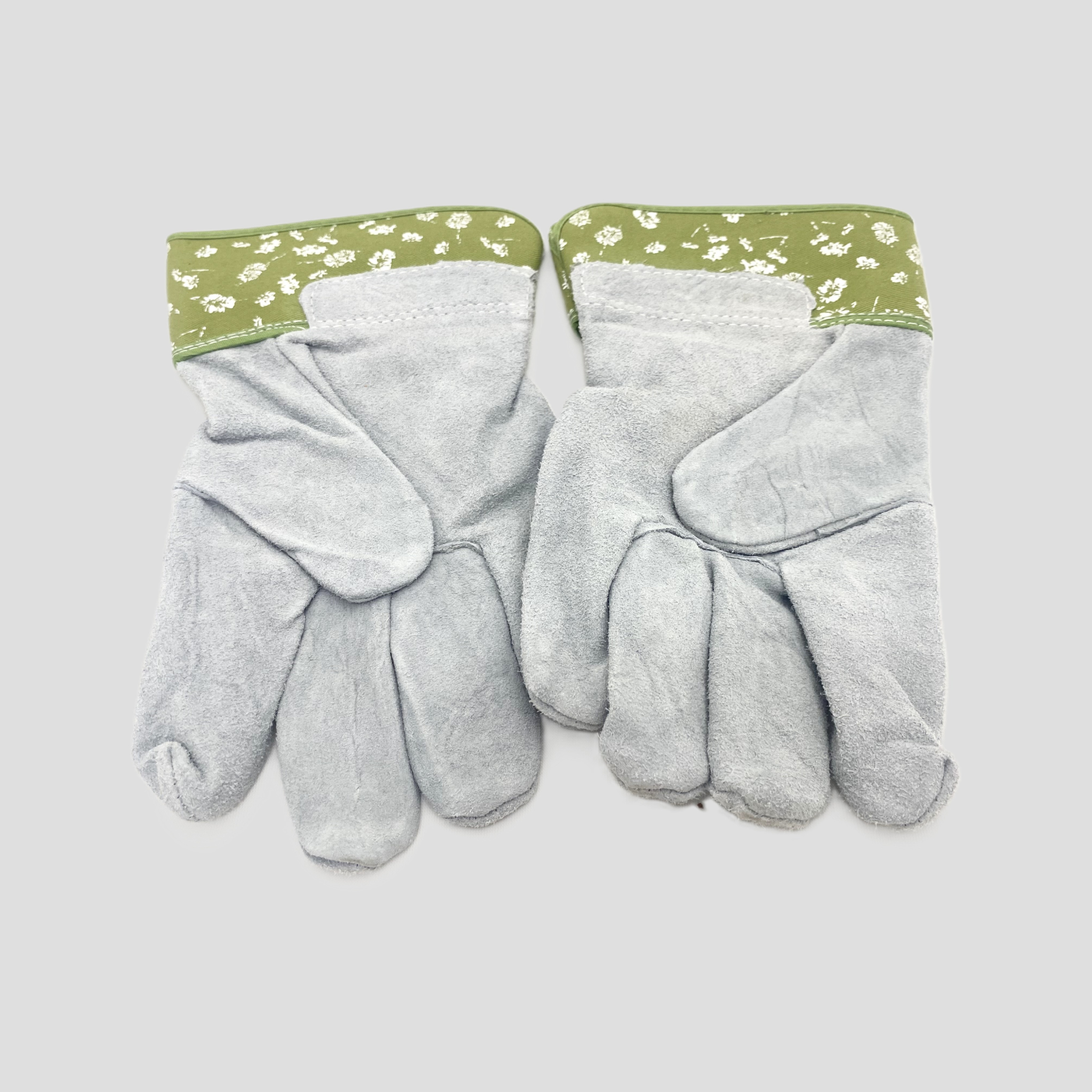 A pair of light gray leather gardening gloves with sage green floral patterned cuffs, displayed flat against a light gray background.