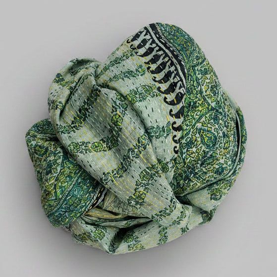 Green patterned scarf rolled up on a textured surface