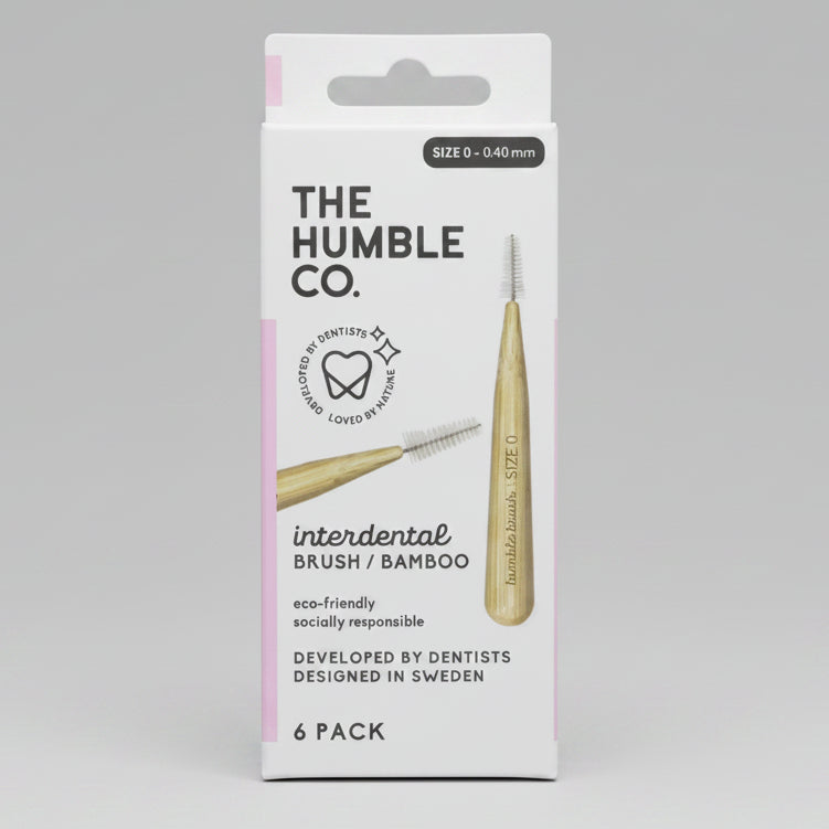 The Humble Co. interdental brush / bamboo 6-pack in its original white cardboard packaging, featuring a bamboo-handled toothbrush and a spoolie, with black text and light pink accents.