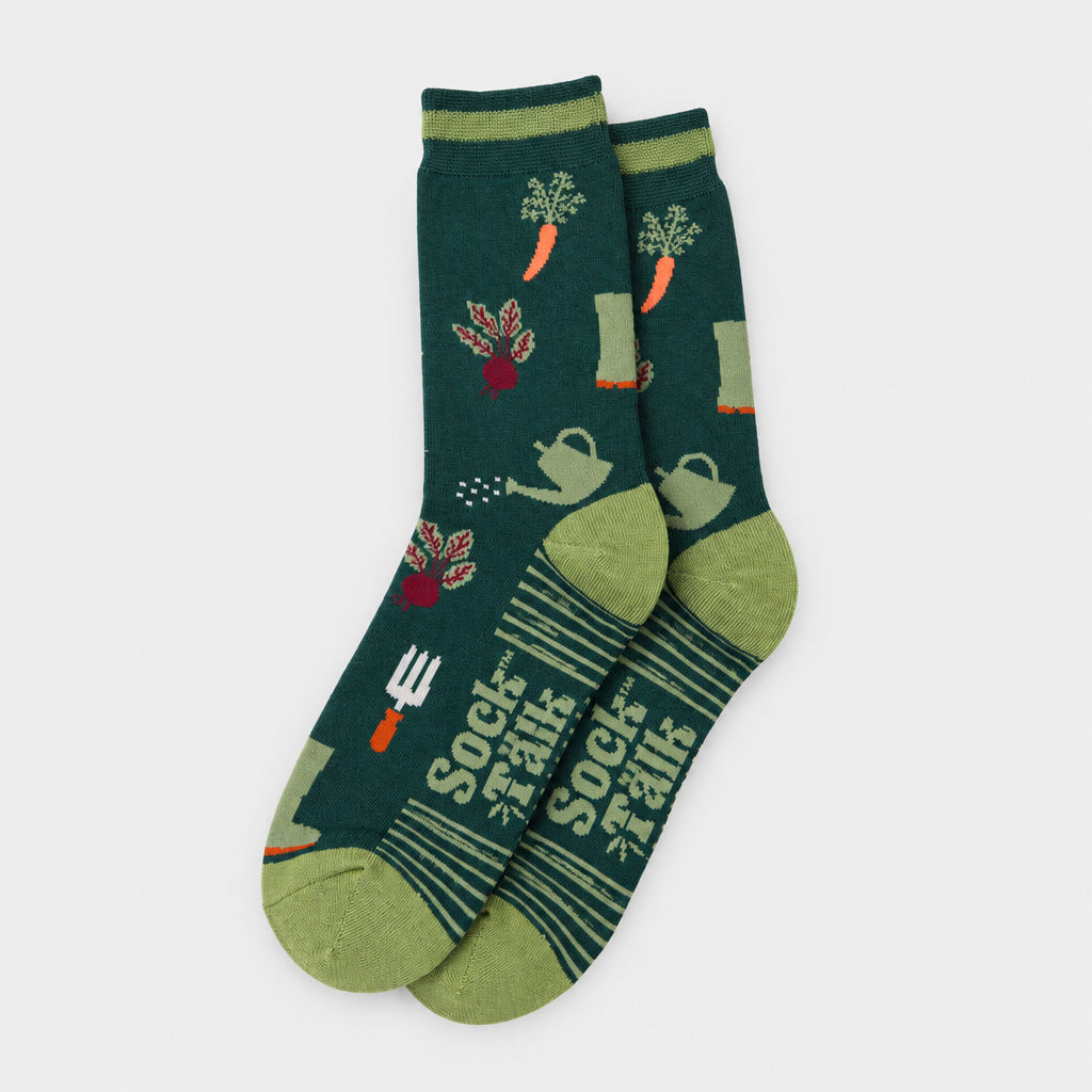 A pair of dark teal crew socks with a gardening pattern featuring carrots, pots, a watering can, and a fork