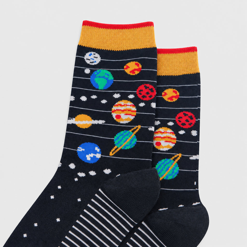 A pair of crew socks with a dark navy blue space-themed pattern featuring colorful planets, stars, and white stripes, finished with a mustard yellow cuff and red trim.