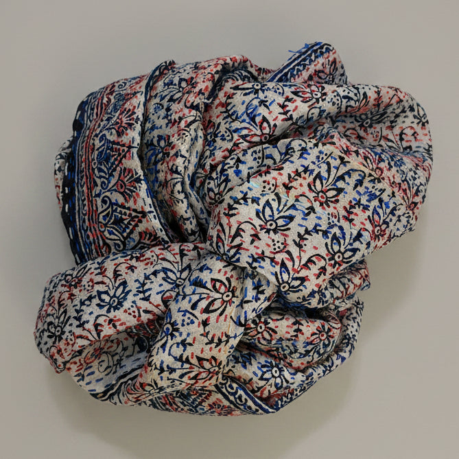 Folded scarf with a floral pattern on a textured beige surface