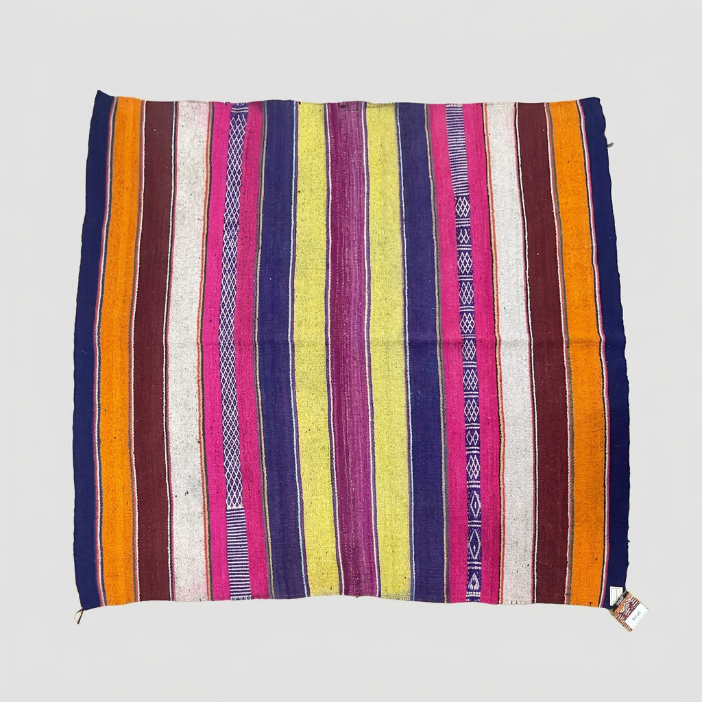 A colorful woven textile rug with vertical stripes in orange, yellow, pink, purple, blue, and white.