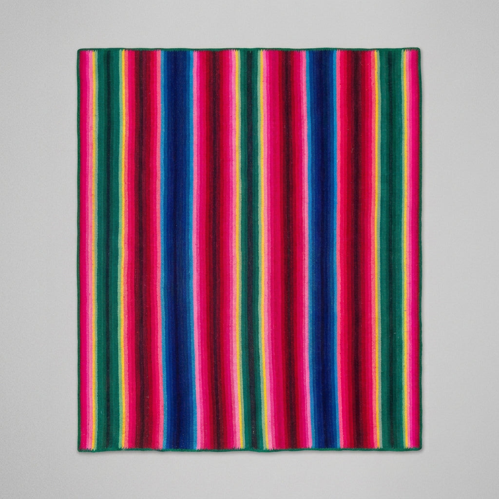 A colorful striped blanket with vertical serape-style stripes in pink, blue, green, yellow, and red, laid flat.