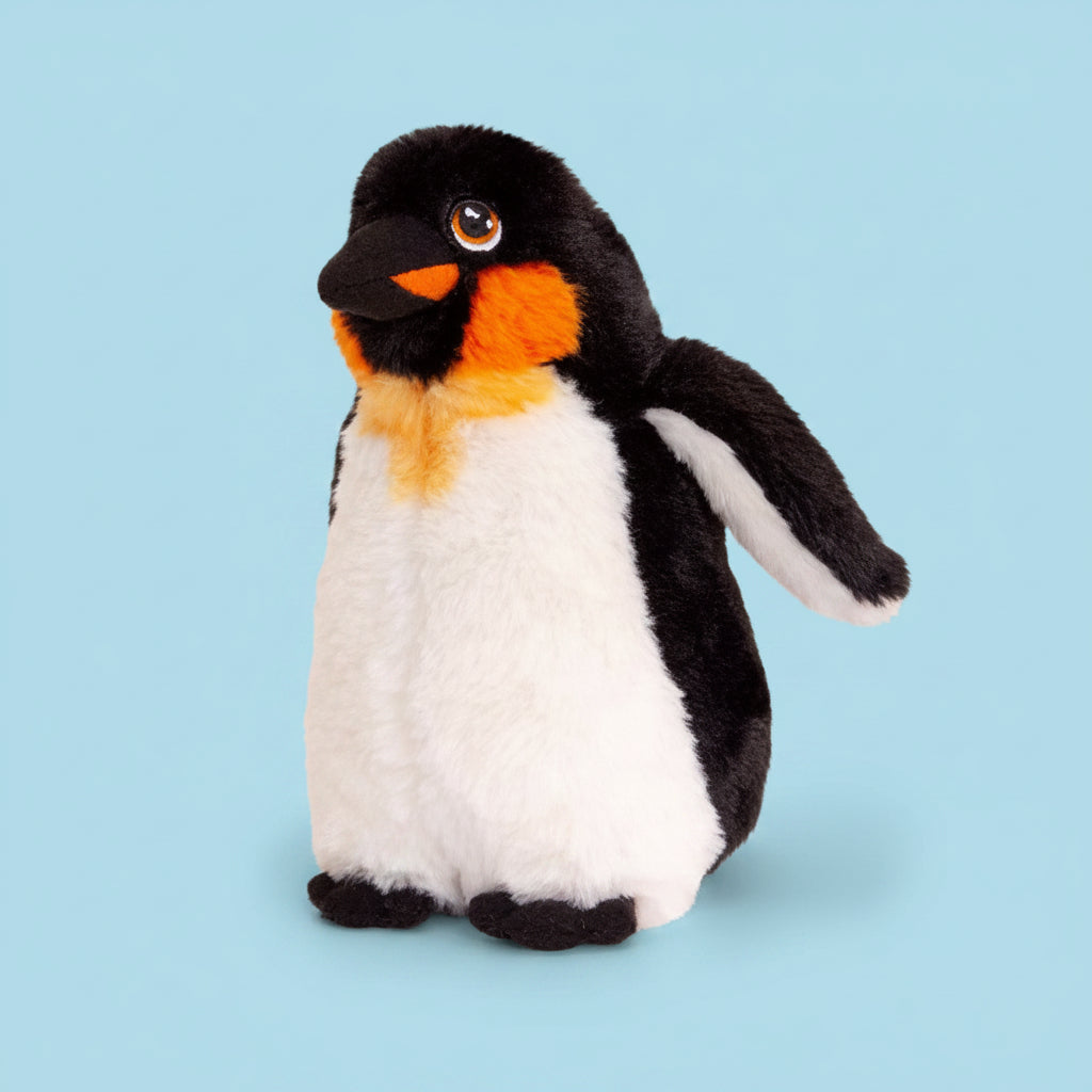 A plush toy penguin with black and white fur, a bright orange chest patch, and a small orange beak, photographed on a clean white background.