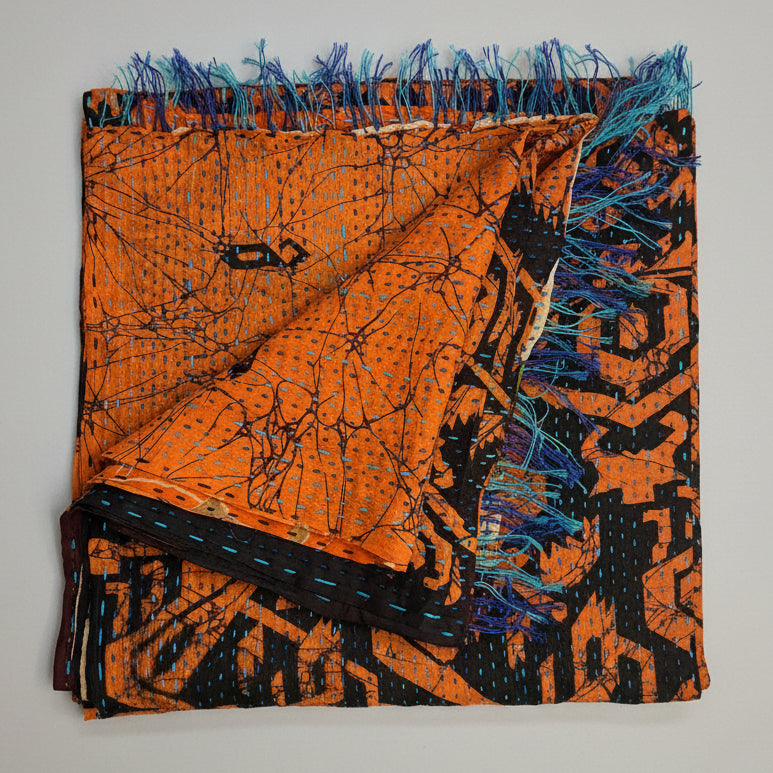Scarf with abstract patterns in orange, black, and blue on a textured beige background
