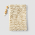 A close-up of a cream-colored, handwoven sisal  bag with a rustic, open-knit texture, featuring a small wooden bead on the left edge.