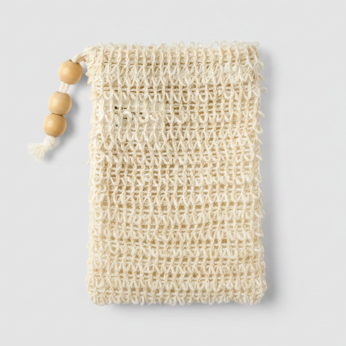 A close-up of a cream-colored, handwoven sisal  bag with a rustic, open-knit texture, featuring a small wooden bead on the left edge.