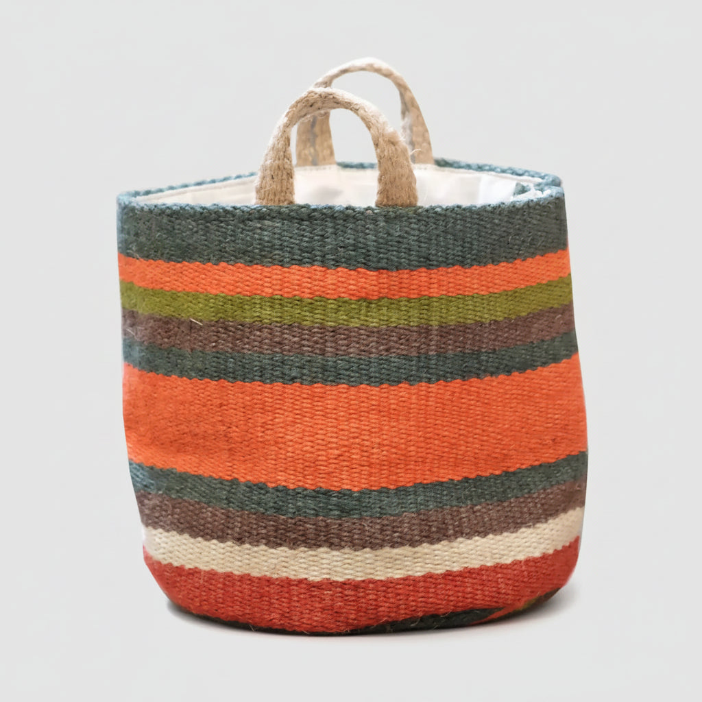 A woven storage basket with horizontal stripes in orange, dark green, brown, beige, and white, featuring two natural jute handles on a white background.