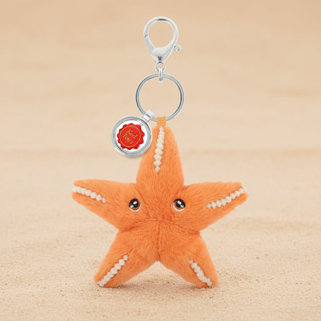 An orange plush starfish keychain with white stitched details, a silver clasp, and a small round red and gold charm, shown on a plain white background.