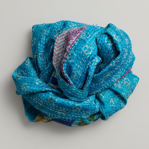 Blue patterned scarf roll on a grey background
