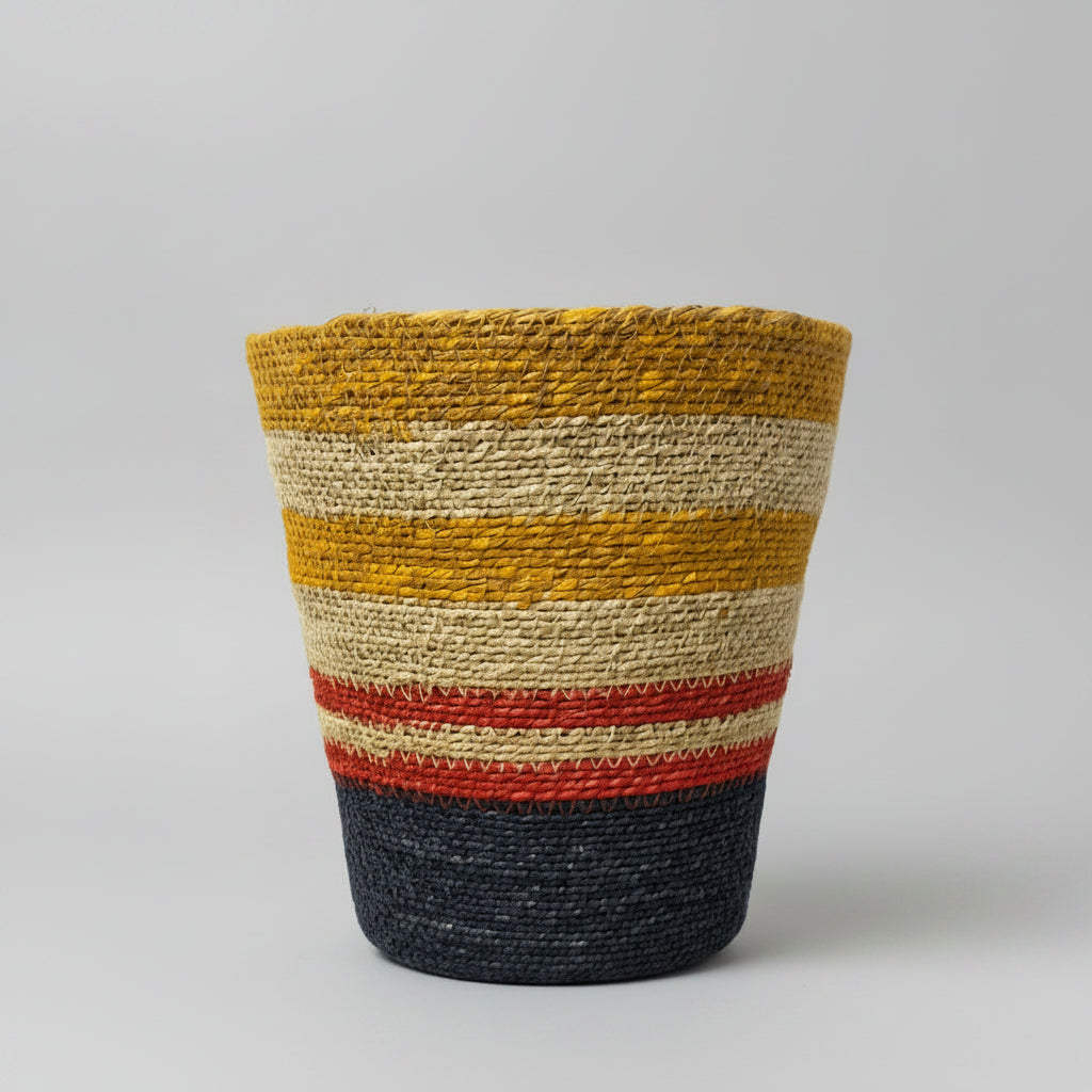 A hand-woven basket with horizontal stripes in mustard yellow, cream, red, and navy blue.