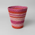 A handwoven basket with horizontal stripes of pink, red, orange, and beige.