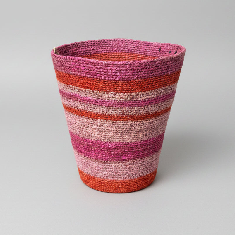 A handwoven basket with horizontal stripes of pink, red, orange, and beige.