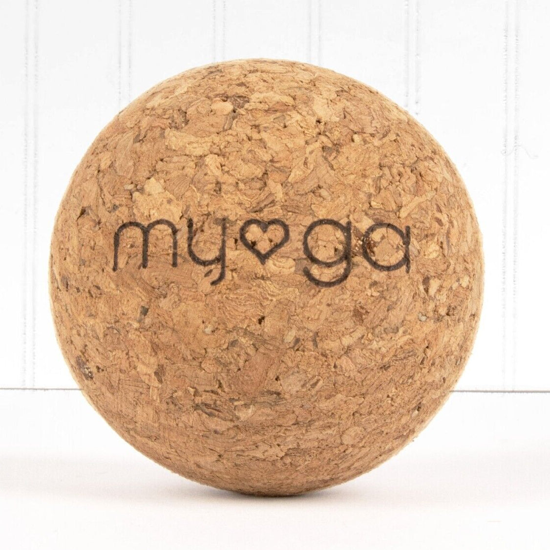 A beige cork yoga block with the brand name 'myga' printed on the front.