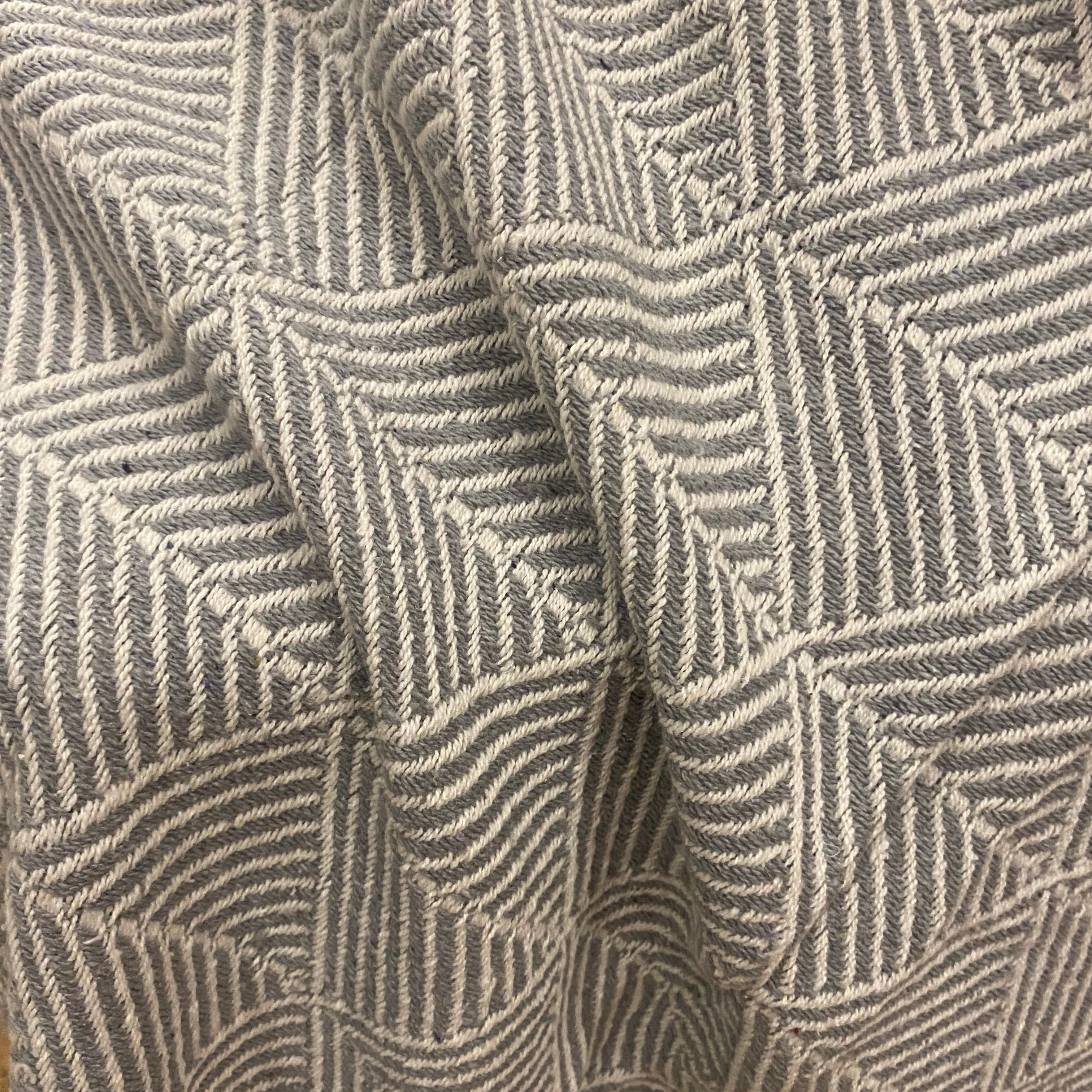 Close-up of a woven textile with a geometric basketweave pattern in taupe and gray.