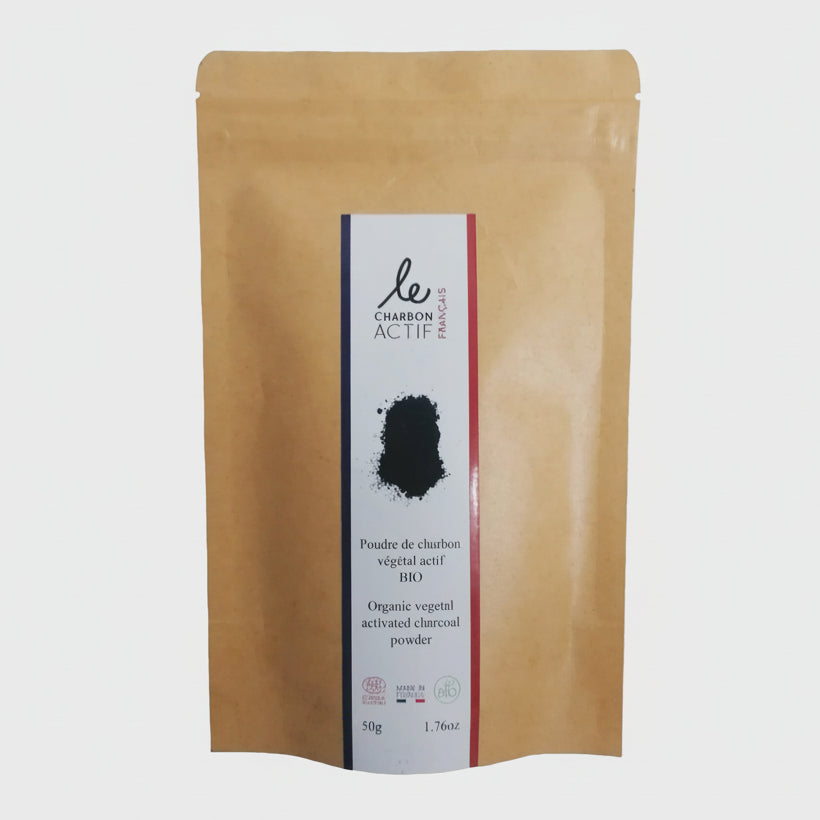 A sealed package of charcoal powder with a label showing the brand and product name, and an illustration of a spoon with charcoal powder in it.