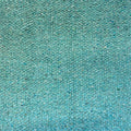A close-up texture shot of a woven fabric or carpet in a mottled teal color, showing a dense, speckled pattern of blue, green, and white fibers.