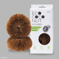 A pair of brown coconut fiber scourers in packaging that highlights their eco-friendly attributes.
